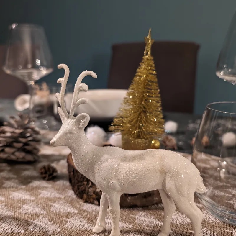 Décor de Noël élégant : cerf blanc et sapin doré sur une table de fête
