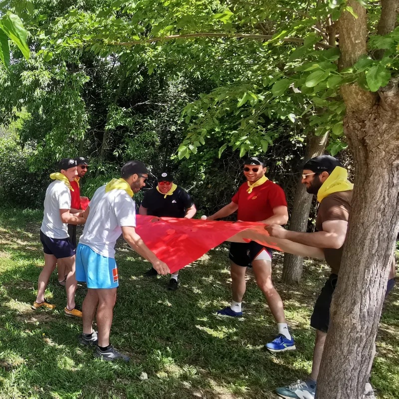 Équipe tendant ensemble une grande toile rouge lors d'un défi collectif en plein air, dans un parc